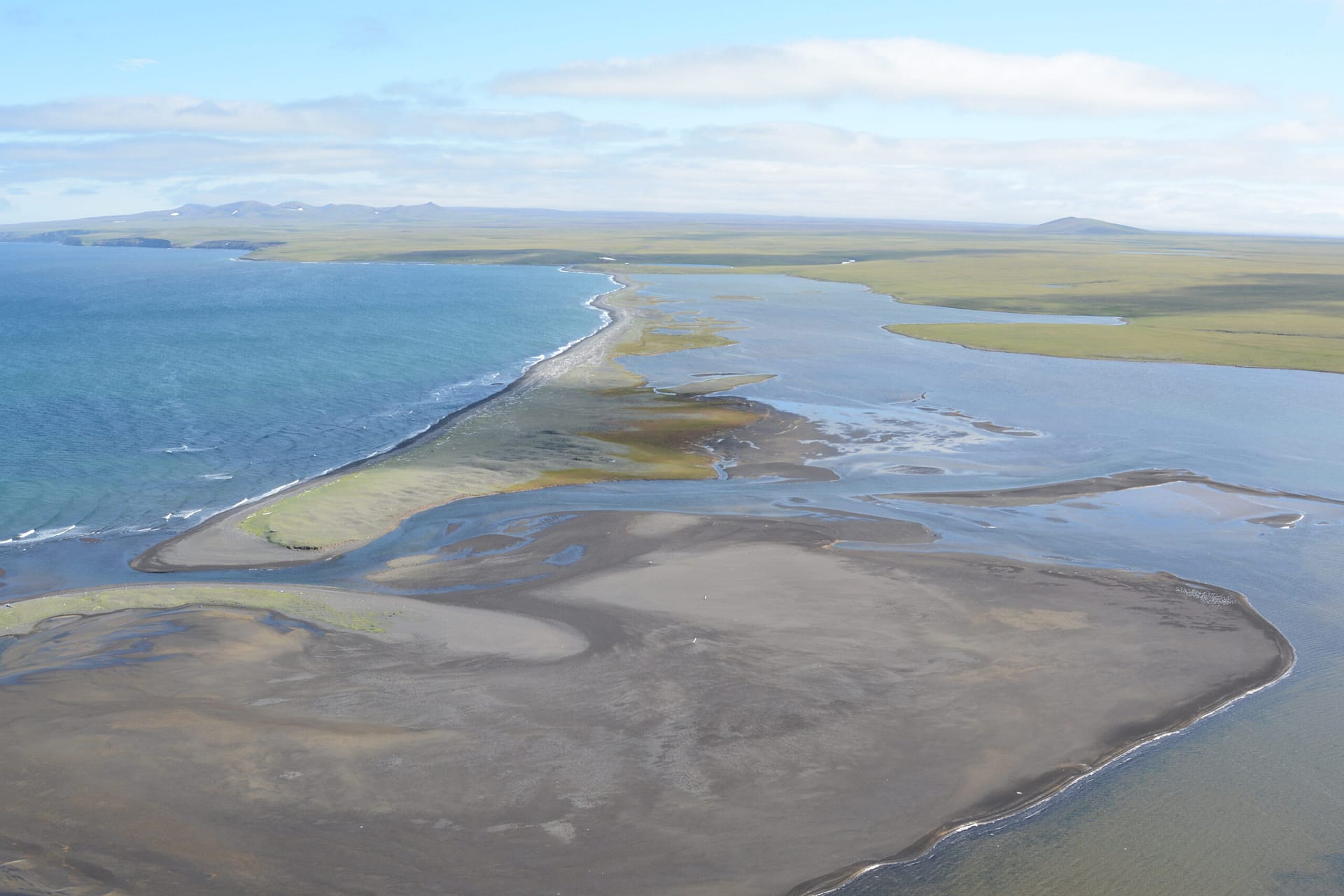 Aerial view of a narrow barrier beach and tidal flats separating the Bering Sea from lagoons and tundra on St. Lawrence Island, Alaska.